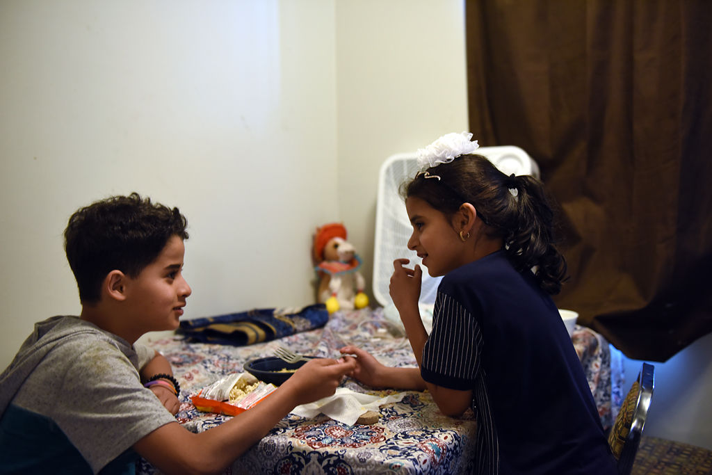 Alhasan Al Hraishawi, 11, and his sister Fatima, 8, eat noodles in their home